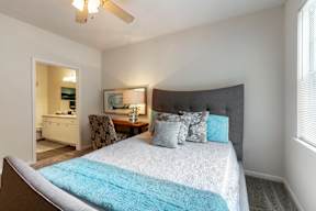 A bedroom with a bed, chair, and a dresser.