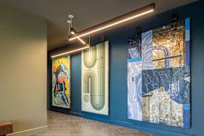 Three paintings hang on a wall in a room.