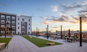 A rooftop patio with tables and chairs overlooks a city skyline.
