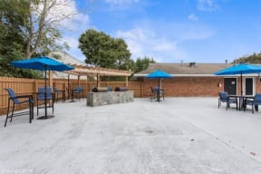 a patio with tables and umbrellas and a fire pit at Courthouse Green Apartments, Virginia, 23832