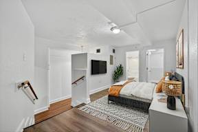 A bedroom with a bed, a TV, and a plant.