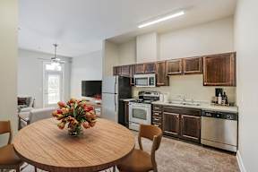 A kitchen with a wooden table and chairs and a vase of flowers on it.