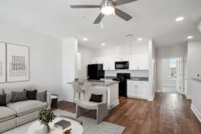 an open living room with a kitchen and a ceiling fan