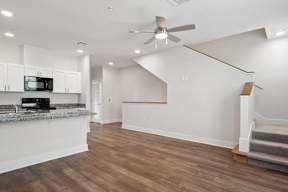 a living room with a kitchen and a ceiling fan