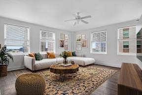A living room with a white couch, a brown ottoman, and a rug.
