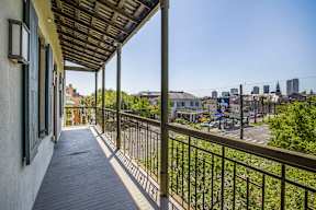 A balcony with a metal railing and a view of a city skyline.
