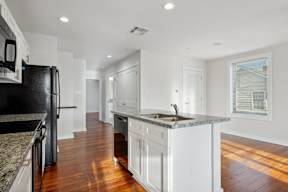 a kitchen with white cabinets and a sink and a black refrigerator