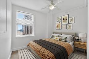 A bedroom with a bed, a ceiling fan, and pictures on the wall.