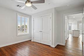 a living room with a ceiling fan and a door to a hallway