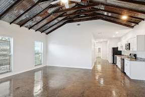 a kitchen with white cabinets and a ceiling with exposed beams