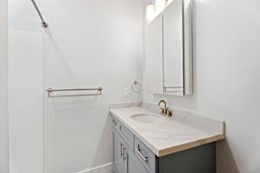 Grove Place II bathroom with a sink, mirror, and a shower.