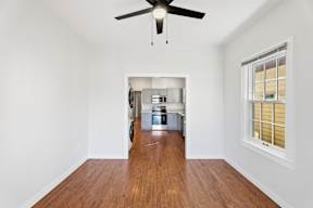 Grove Place II room with a ceiling fan and a kitchen in the background.