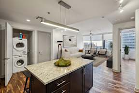A kitchen with a marble countertop and dark wood floors.