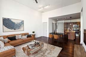 A living room with a brown couch and a painting on the wall.