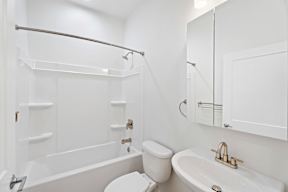 Grove Place II white bathroom with a toilet, sink, and bathtub.