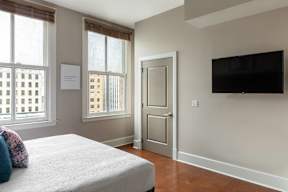 A bedroom with a bed, a door, and a window.