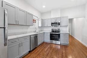 Grove Place II modern kitchen with stainless steel appliances and wooden floors.