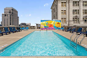 A large outdoor swimming pool with a mural on the wall.