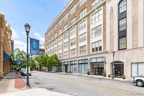 A street view of a city with a building on the right and a car parked on the sidewalk.