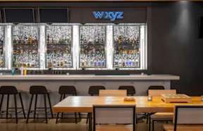 A bar with a WXYZ sign above it has a counter with bottles on it.