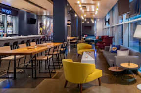 A modern dining area with wooden tables and yellow chairs.