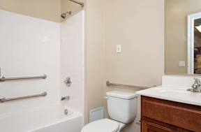 A white toilet sits next to a white bathtub in a bathroom.