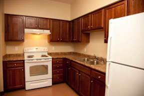 A kitchen with brown cabinets and a white refrigerator.