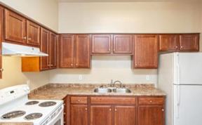 A kitchen with wooden cabinets and a white stove top oven.
