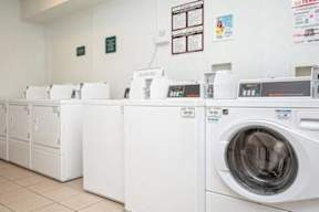 A row of white front load washing machines in a laundromat.