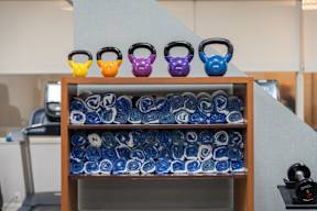 A shelf with kettlebells and towels in a gym.