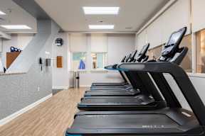 A gym with treadmills and a clock on the wall.
