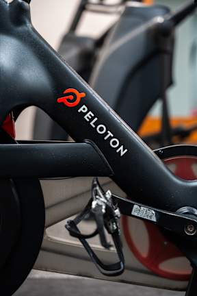 Peloton bike seat with a red logo and black background.