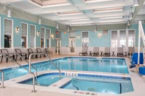 A large indoor swimming pool with a blue tiled edge and a white floor.