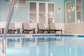 A pool with chairs and a blue wall.