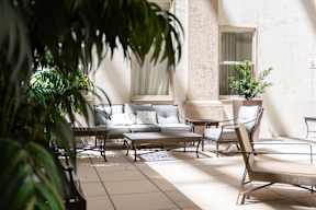 A patio with a table and chairs is bathed in sunlight.