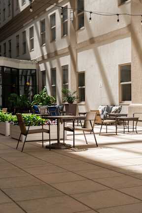 A patio with a table and chairs is bathed in sunlight.