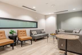 A waiting room with brown chairs and a grey couch.