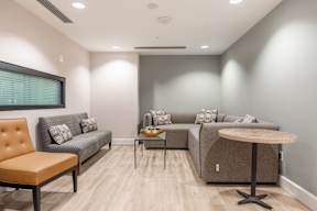 A living room with a grey couch, a brown chair, and a wooden table.