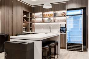 A modern kitchen with a white countertop and black bar stools.
