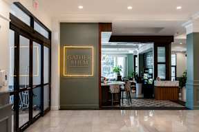A modern dining area with a neon sign that says "Gather & Hem".