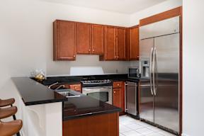 A kitchen with a black counter top and stainless steel appliances.