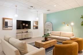 A living room with a sofa, chairs, and a television.