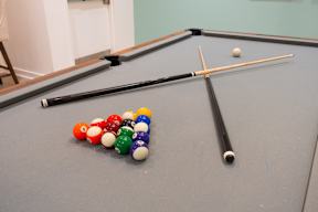 A pool table with a white ball, a cue stick, and a set of numbered balls.