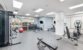 A gym with a variety of equipment including a squat rack, bench press, and a medicine ball.