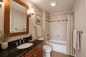 A bathroom with a black granite countertop and a white toilet.