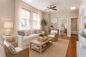A well-lit living room with a sofa, armchair, and coffee table.