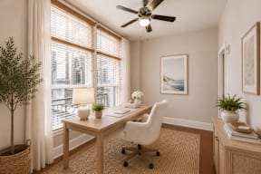 A room with a desk, chair, and a ceiling fan.