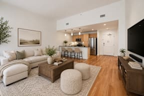 A modern living room with a white sofa, a wooden coffee table, and a large painting on the wall.
