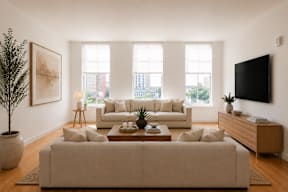 A living room with a large couch, a coffee table, and a flat-screen TV mounted on the wall.