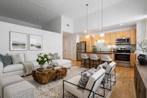 A modern kitchen with a breakfast bar and a living room area with a couch, chairs, and a coffee table.